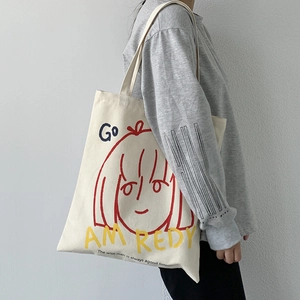 Off-white canvas tote bag with artistic girl print and slogan shown on shoulder