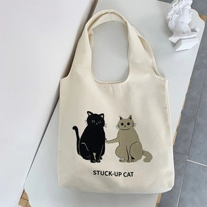 Detail of artistic canvas tote bag featuring minimalist cartoon cats on white background