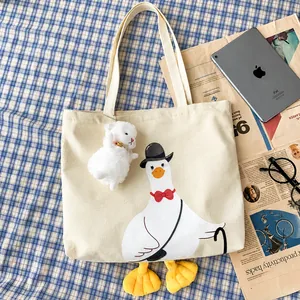 Flat lay of a cute duck canvas tote bag with 3D feet and a plush sheep pendant