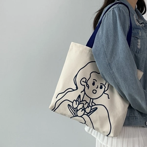 Detail der künstlerischen Mädchen-Illustration auf cremeweißer Canvas-Tasche am Modell