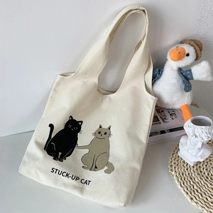 Close-up of cream canvas tote bag with cute stuck-up cat print and soft cotton texture