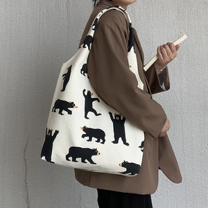 Close-up of thick canvas tote bag featuring black bear prints and a sturdy shoulder strap