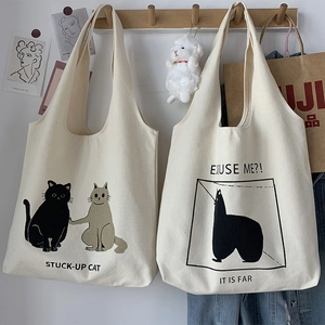 Detailed view of canvas tote bags with cute cat illustrations hanging on wooden hooks