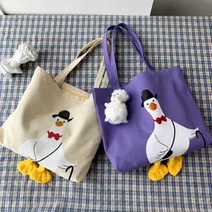 Detail of canvas tote bags featuring cartoon duck prints and yellow plush feet accents
