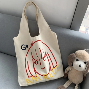 Detail of a beige canvas tote bag with artistic girl print resting on a cozy sofa