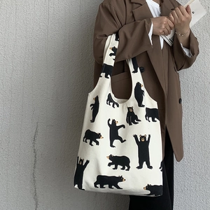 Detailed view of large white canvas tote bag featuring cute cartoon black bear prints