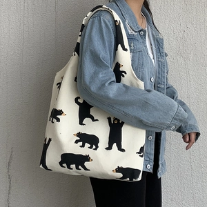 Detail of canvas tote bag featuring cute cartoon bear patterns and sturdy shoulder straps