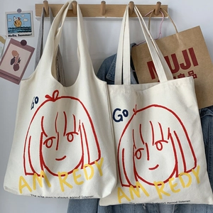 Detail of canvas tote bags with red cartoon face print and yellow lettering in a cozy room