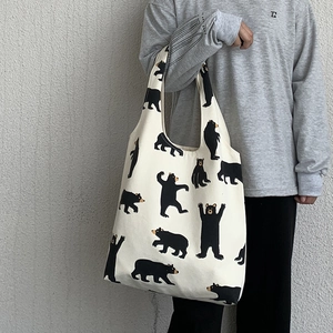 Detail of off-white canvas tote bag featuring cute black cartoon bear prints and wide strap