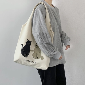 Detail shot of a beige canvas tote bag with cat illustration and STUCK-UP CAT text