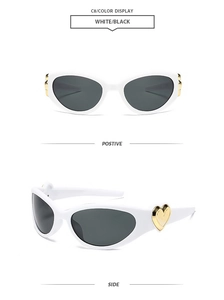 Close-up of white cat-eye sunglasses with gold heart-shaped temple detail and black lenses