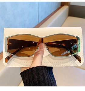 Detail view of amber one-piece sunglasses with silver metal frame and quilted leather pouch