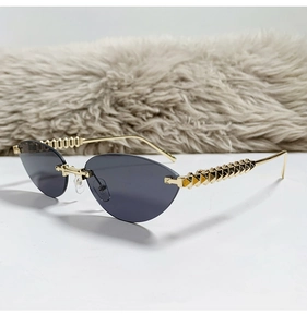 Detail of rimless cat-eye sunglasses with gold textured铆钉 metal temples on plush backdrop