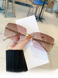 Close-up of frameless square sunglasses with gradient lenses and engraved metal temples