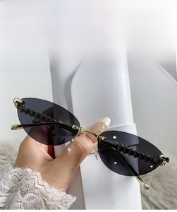 Detail of rimless cat-eye sunglasses with grey lenses and gold metal textured temples