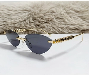 Detailed macro view of gold pyramid studded temples on frameless cat-eye sunglasses