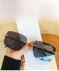 Close-up of grey rimless sunglasses featuring unique black wave-shaped temple design
