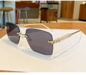 Close-up of rimless square sunglasses with gold metal temples and rivet decorative detail