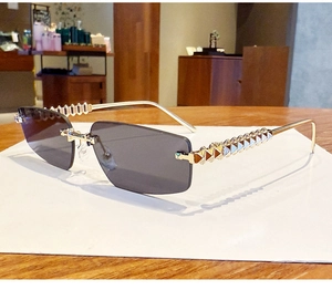 Close-up of golden punk-style studded metal temples on rimless rectangle sunglasses