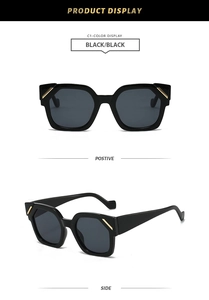 Detail view of black polygon sunglasses with wide temples and golden metal accents
