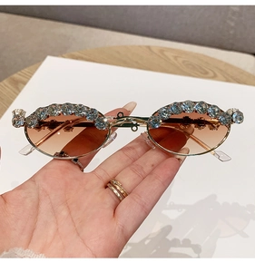 Close-up of oval sunglasses with brown gradient lenses and large crystal rhinestones