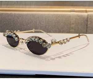 Close-up of luxury gold metal oval sunglasses with sparkling rhinestone embellishments