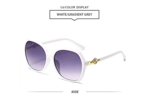 Side view of white oversized sunglasses with golden rose detail on the temples