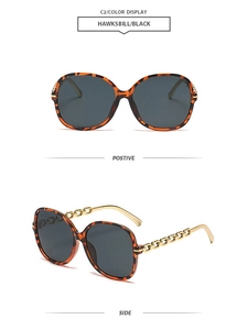 Vue détaillée de lunettes de soleil écaillées avec branches en chaîne dorée et verres noirs