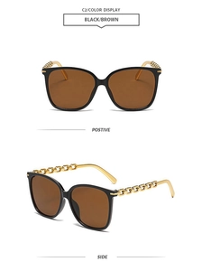 Detail view of square black sunglasses with gold metal chain arms and brown lenses
