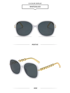 Détail de lunettes de soleil blanches avec branches en chaîne dorée et verres noirs fumés
