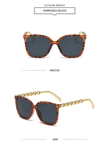 Detail view of square hawksbill sunglasses with gold chain temples and grey lenses