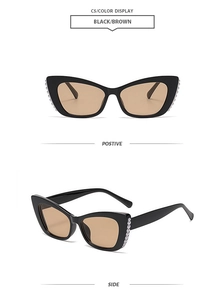 Detail view of black cat-eye sunglasses with white pearls on the frames and brown lenses