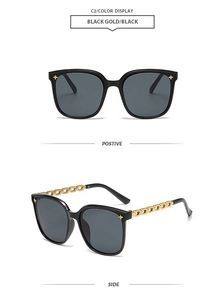 Detail of square oversized black sunglasses featuring golden chain temples and star accents