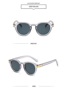 Detail of grey translucent jelly sunglasses with gold metal rivets and dark lenses