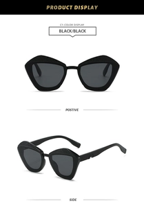 Detail of oversized black geometric cat-eye sunglasses with textured upper frame rims