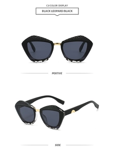 Detail view of black oversized cat-eye sunglasses with gold metal bridge and snakeskin texture