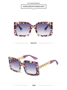 Detail of square sunglasses with purple floral frame and gold chain link temples