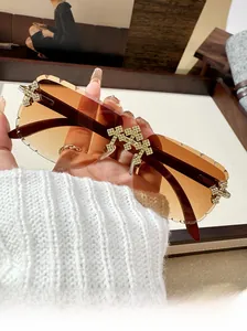 Close-up of rimless square sunglasses with brown gradient lenses and rhinestone crosses