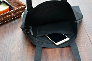 Dettaglio della borsa tote in tela nera con chiusura a zip e tasca interna per cellulare