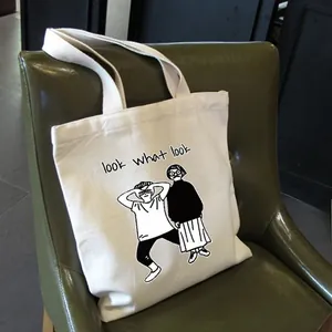 Dettaglio della borsa tote in tela bianca con illustrazione nera su una sedia vintage