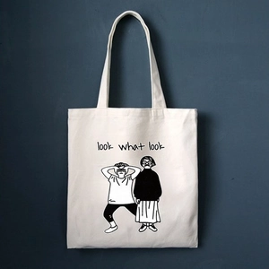 Dettaglio di borsa tote in tela beige con illustrazione cartoon e scritta look what look