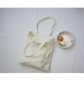 Flat lay of cream canvas tote bag with supermarket receipt print on white fabric