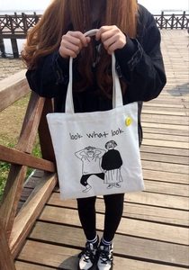 Dettaglio della borsa in tela bianca con grafica comic e spilla gialla con smiley