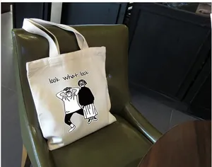 Dettaglio di una borsa tote in tela beige con illustrazione a fumetti su sedia in pelle