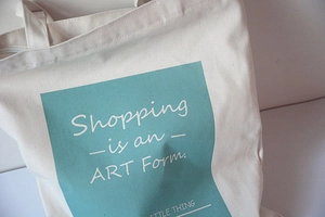 Close-up of canvas tote bag with green block print and Shopping is an Art Form text
