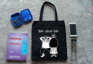 Piatto di una borsa tote in tela nera con illustrazione grafica e oggetti quotidiani