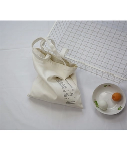 Detail of minimalist white canvas tote bag with black receipt style typography