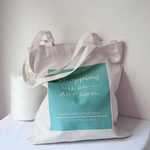 Detail of white canvas tote bag with teal graphic print and artistic shopping text