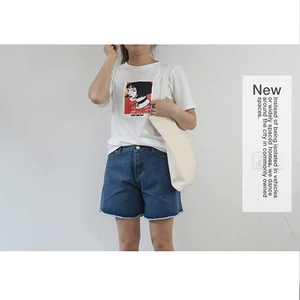 Detail of a minimalist white canvas bag paired with a Mathilda graphic t-shirt and denim shorts