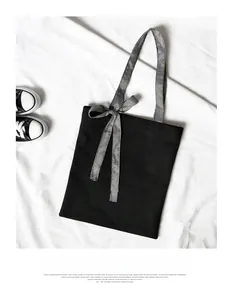 Detail of minimalist black canvas tote featuring a black and white gingham bow handle